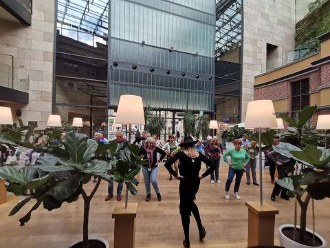 Na zdjęciu przestrzeń architektoniczna wewnątrz Capitol oraz dużo osób na zajęciach tanecznych.  