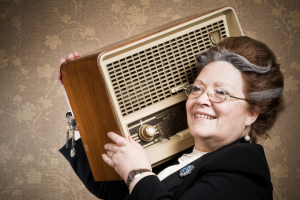 Na zdjęciu widać seniorkę trzymającą radio